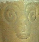 Human head with rams horn carving